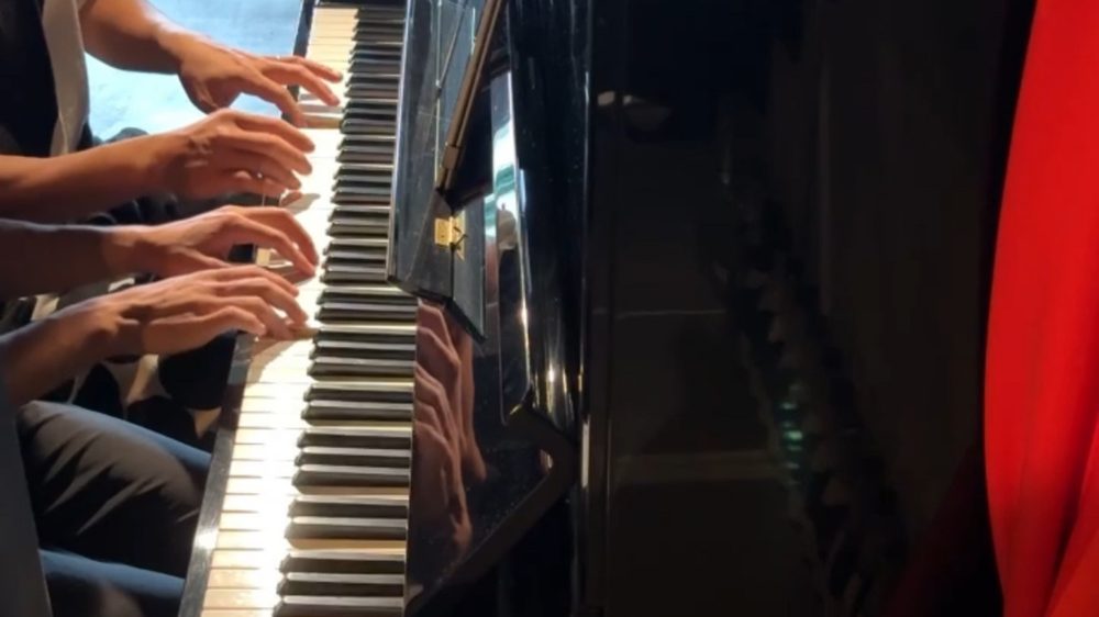 Four hands playing piano together at a musicand piano pod in Kyoto